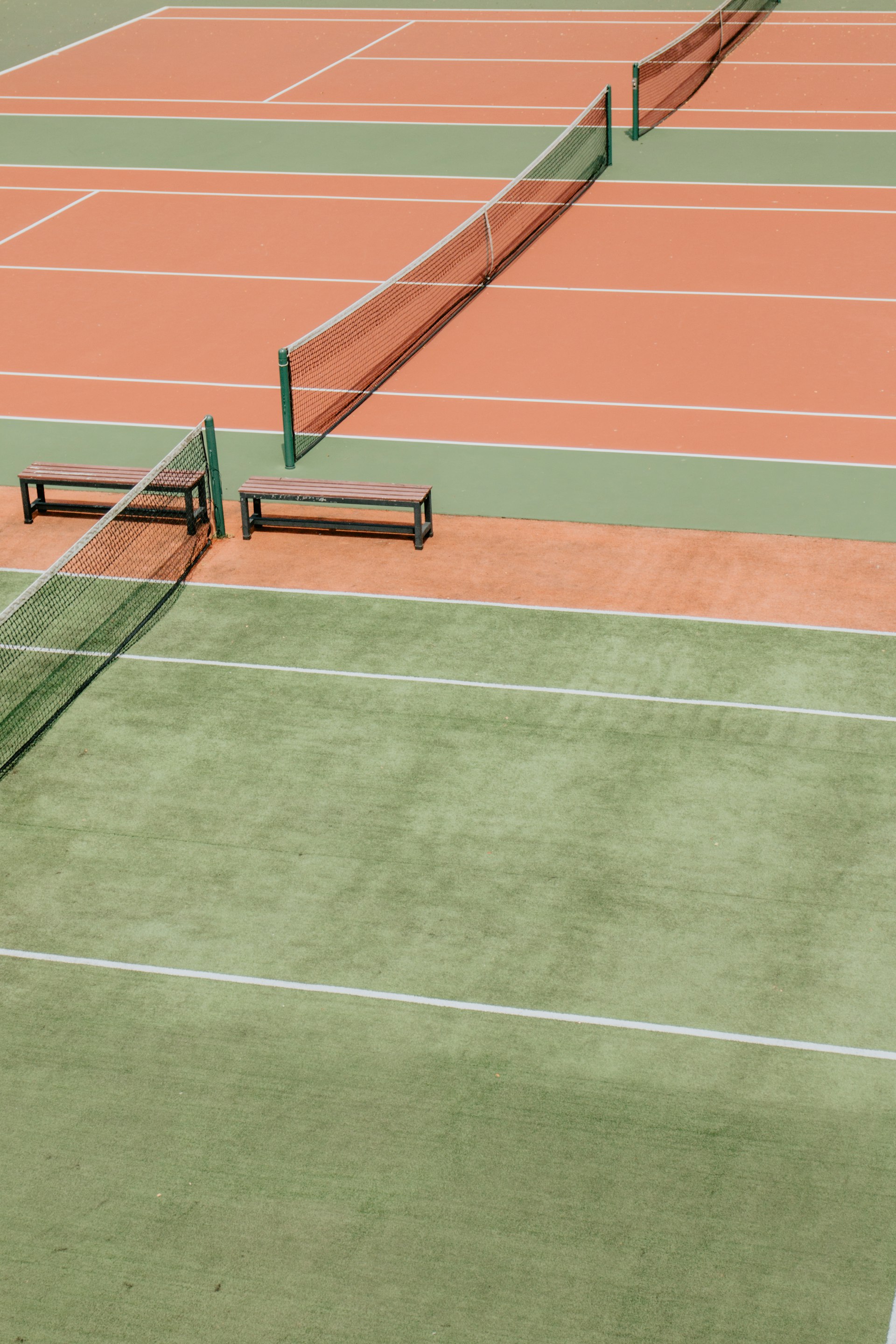 Outdoor tennis courts from above, with clay and green playing surfaces